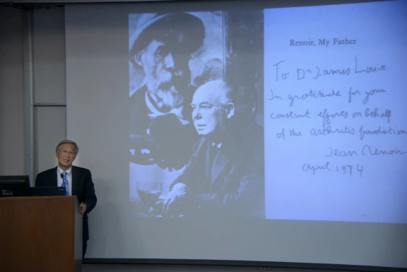 James Louie presenting before a projected image of men