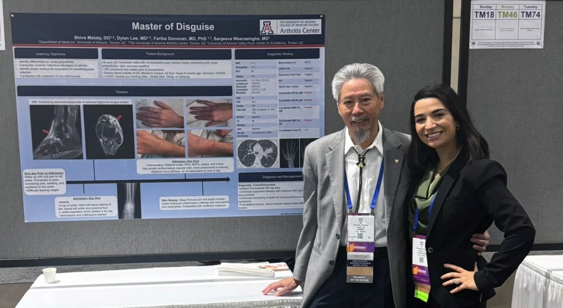 director kwoh and a fellow in front of research poster