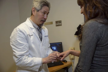 dr. kwoh examining a patients hand